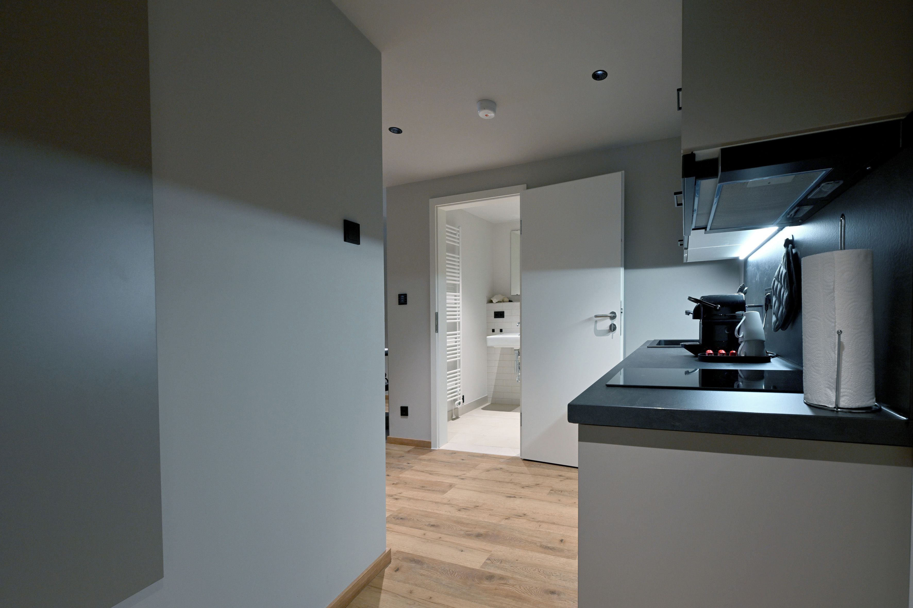 A modern kitchen with a black countertop, a coffee machine, and a paper towel dispenser.