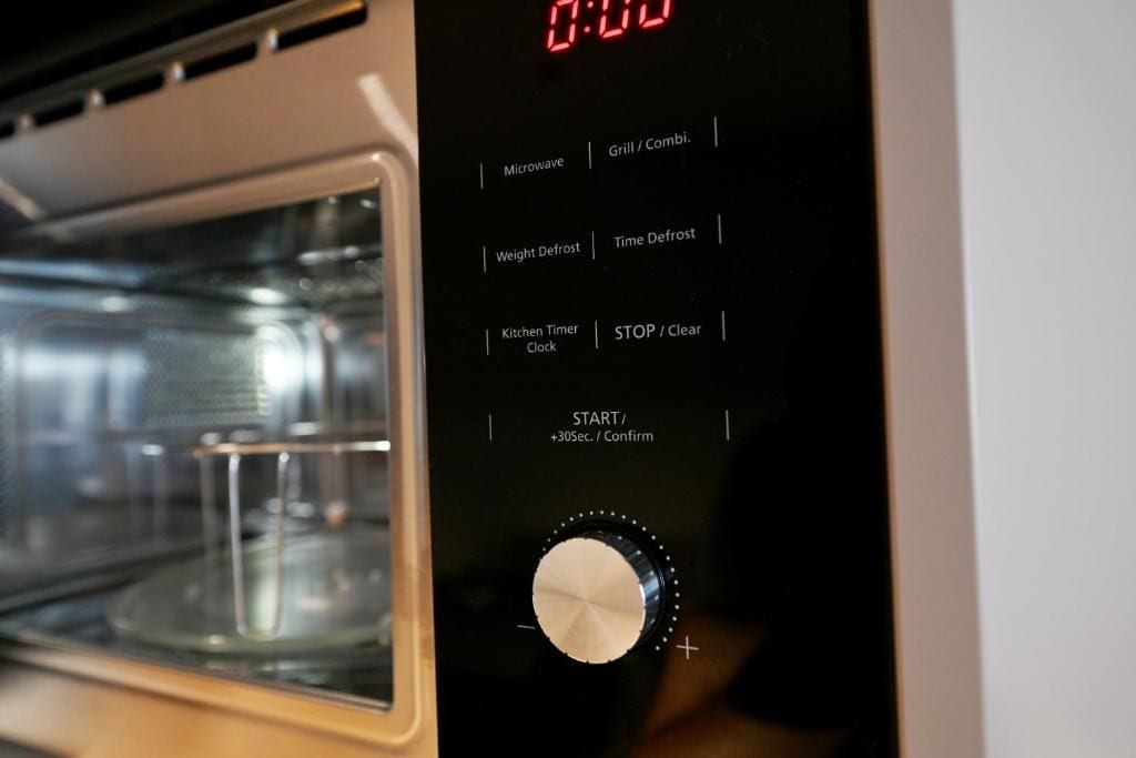 A microwave with a digital display, control buttons, and a timer knob.