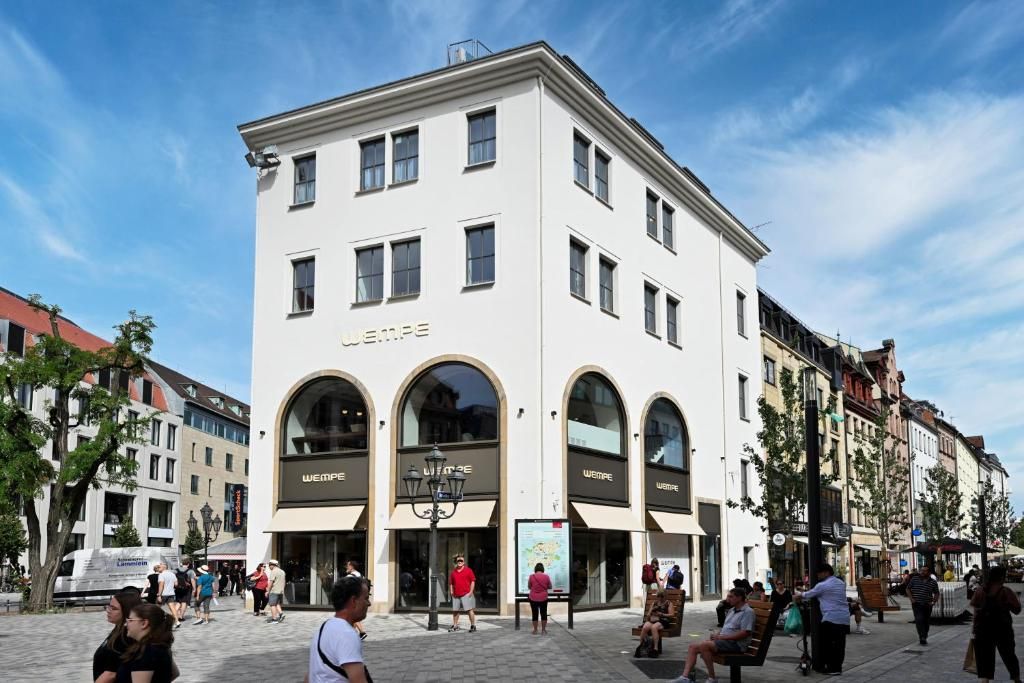 A building with the name 'WEMPE' on the facade, featuring arched windows and a flat roof.