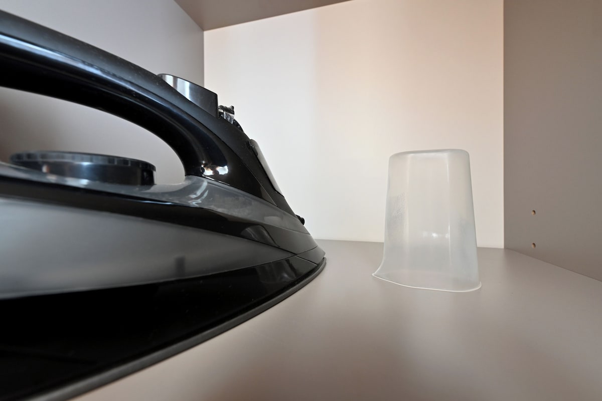 Parte delantera izquierda de un coche con un vaso de plástico transparente sobre una superficie plana.