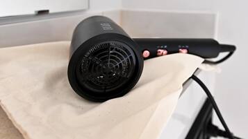 A hair dryer with a cord and a power strip on a beige surface.
