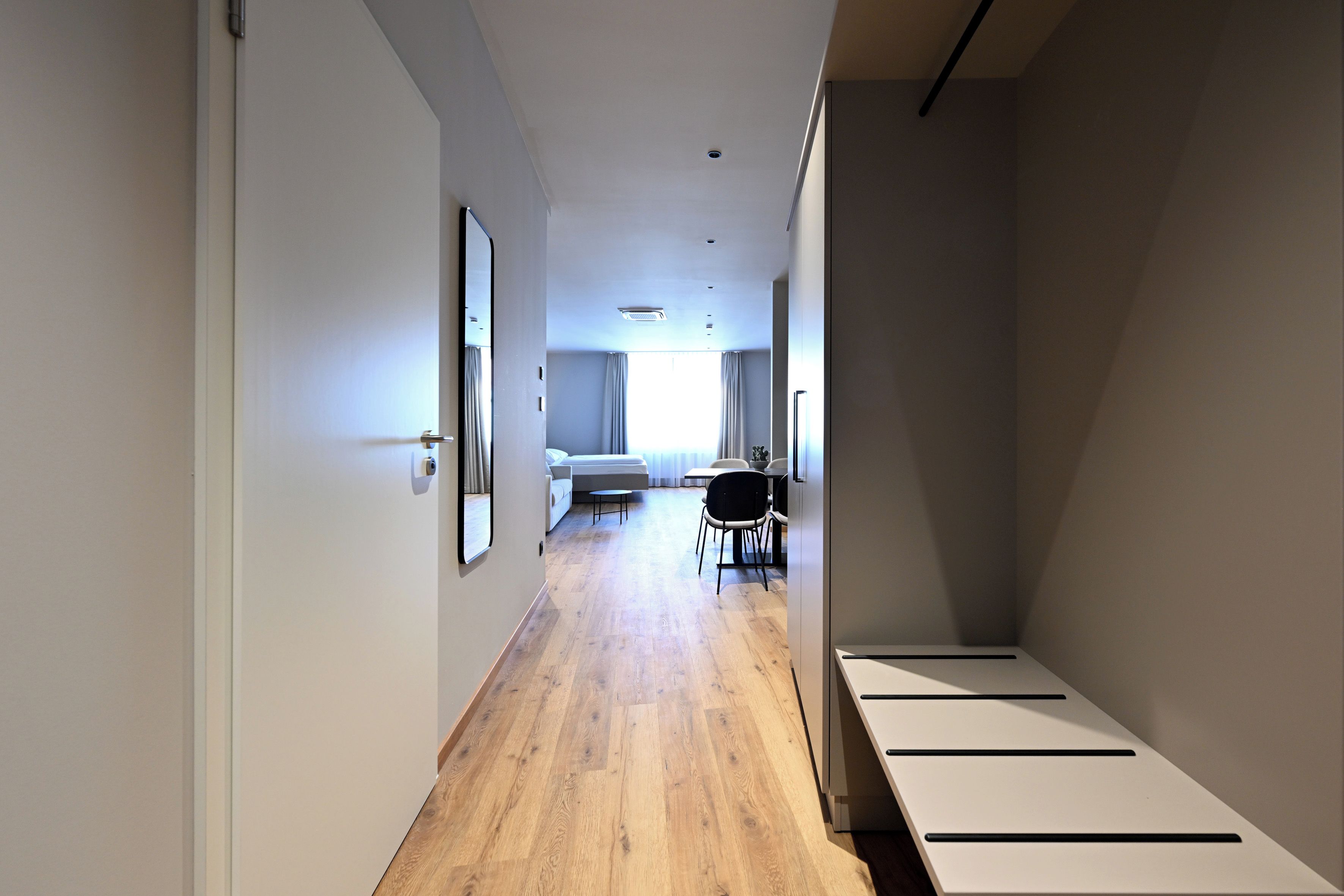 Una habitación de hotel moderna con piso de madera, una cama, un escritorio y una silla.