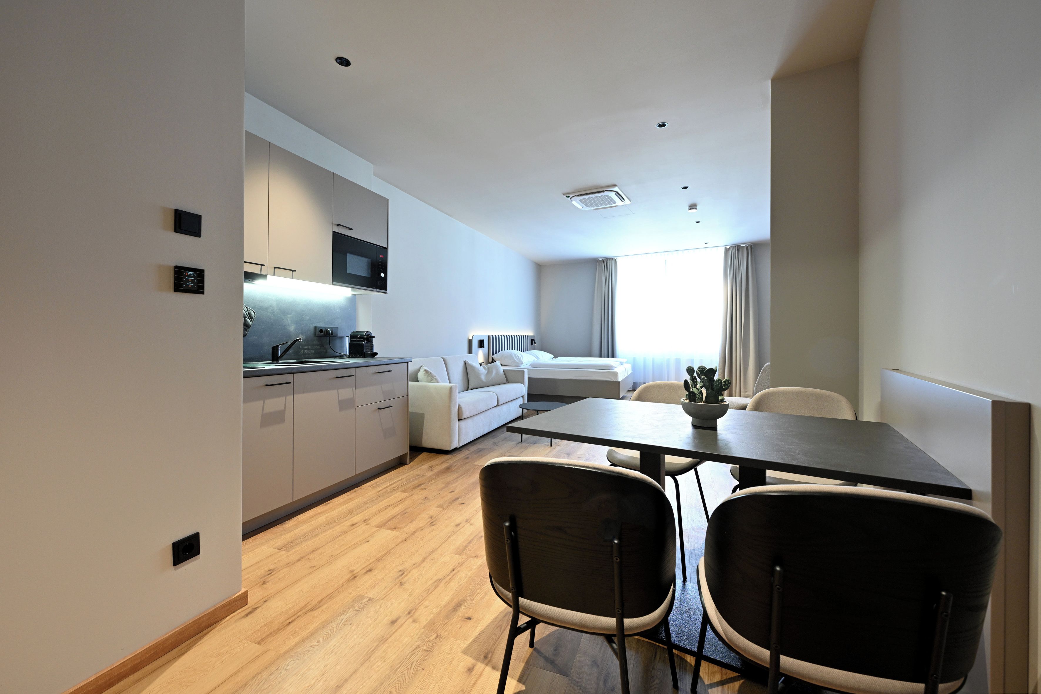Une cuisine moderne dotée d’appareils électroménagers intégrés, un coin repas avec une table et des chaises, et un espace de vie comprenant un canapé et un lit.