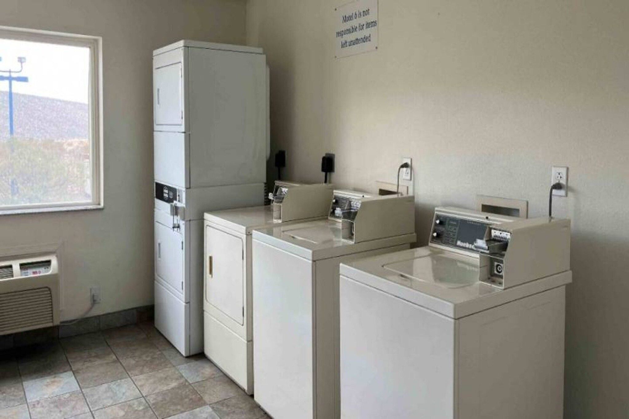 A laundry room with a dryer, washing machine, and a sign warning about unattended items.