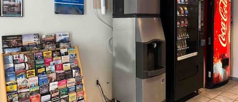 Una máquina expendedora, un refrigerador y una selección de libros de viajes.