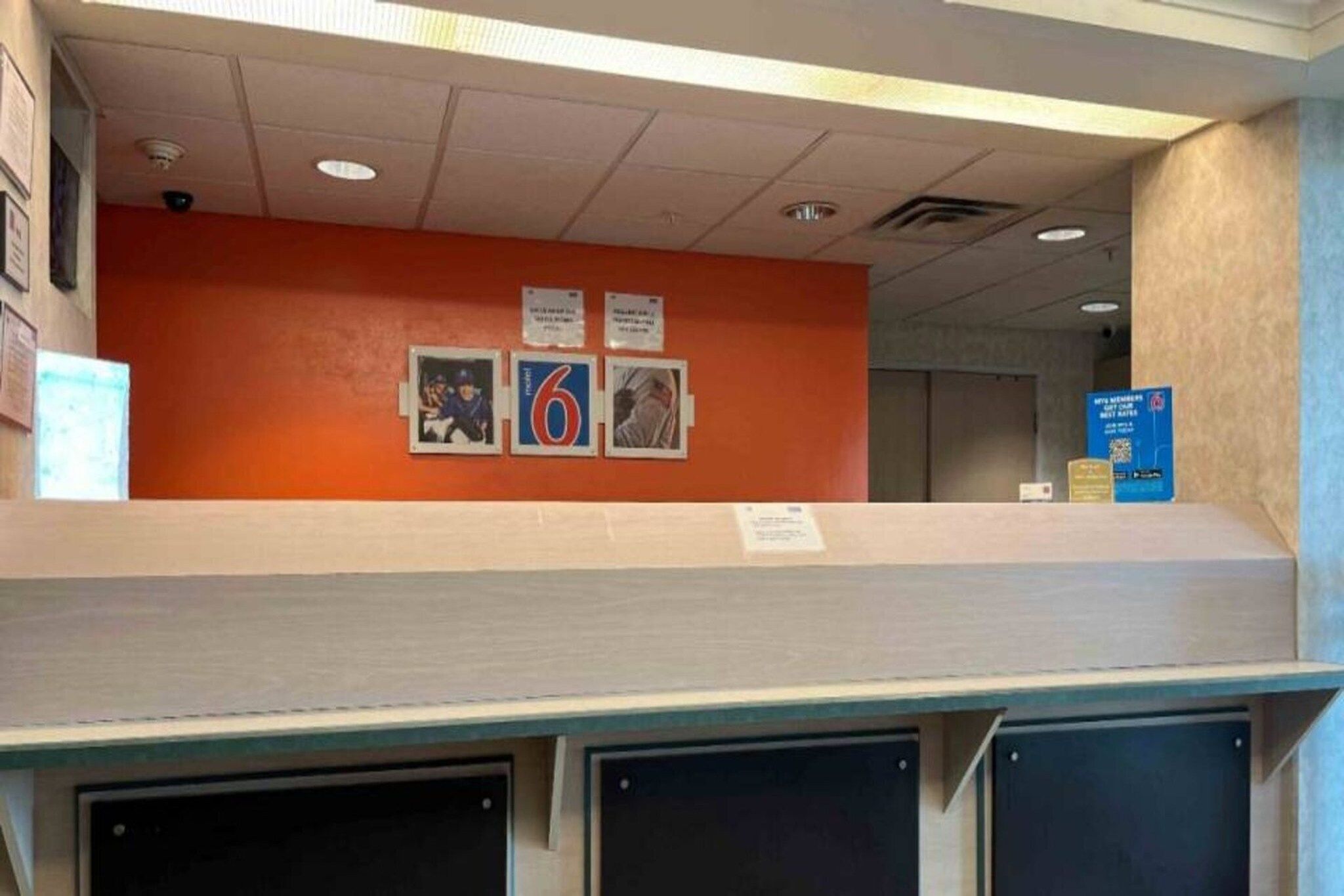 A reception area with a counter, a wall with framed photos, and a blue sign with QR code.