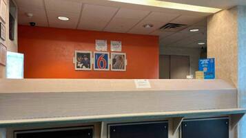 A reception area with a counter, a wall with framed photos, and a blue sign with QR code.