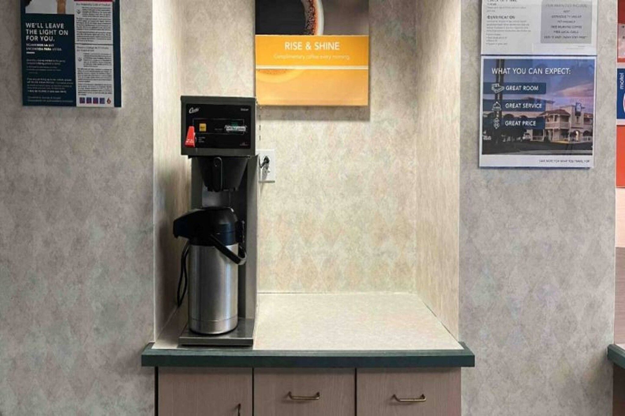 A coffee machine on a countertop with a sign above it that reads 'RISE & SHINE'.