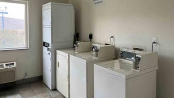 A laundry room with a dryer, washing machine, and a sign warning about unattended items.