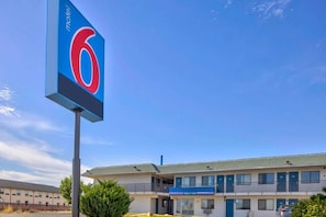 A motel with a prominent '6' sign, a parking lot, and a building with a 'Welcome' sign.