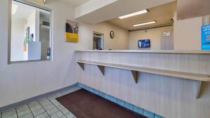 Ein Empfangsbereich mit einer Rezeption, einer Uhr und einem Monitor an der Wand.