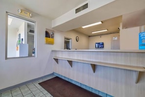 A reception area with a reception desk, a clock, and a monitor on the wall. - Cozy 2-bed Room|Pool|Free Parking (TUCUMCARI)
