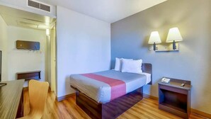 Ein Hotelzimmer mit Bett, Nachttisch, Stuhl und Schreibtisch.