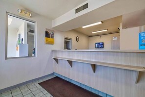 A reception area with a reception desk, a clock, and a monitor on the wall. - 1 QUEEN BED | MICFRIDGE (TUCUMCARI)