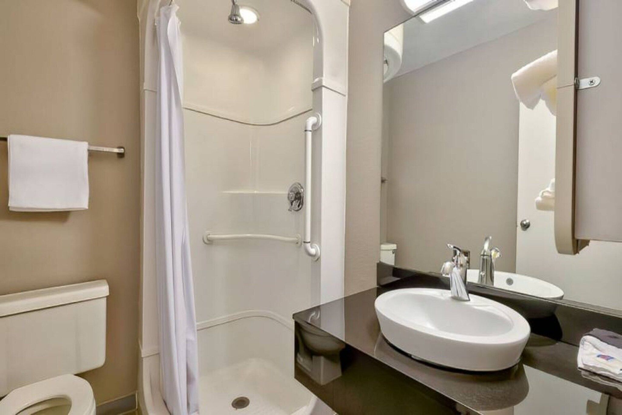 A modern bathroom with a walk-in shower, a large sink, and a mirror.