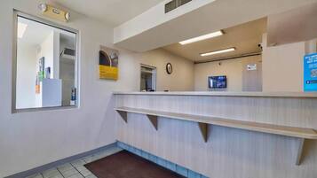 A reception area with a counter, a clock, and a small window.
