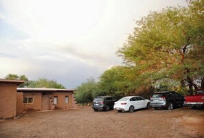 A gravel parking area with a building and trees.