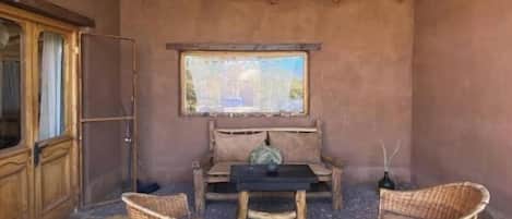A room with a thatched roof, a wooden cabinet, a table with chairs, and a painting on the wall.