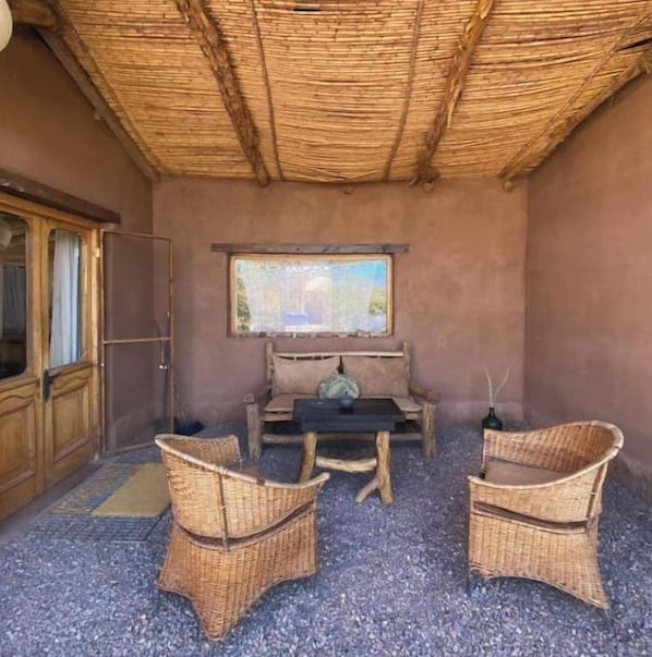 A room with a thatched roof, a wooden cabinet, a table with chairs, and a painting on the wall.