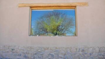 Une fenêtre donnant sur un arbre se détachant sur un ciel dégagé.