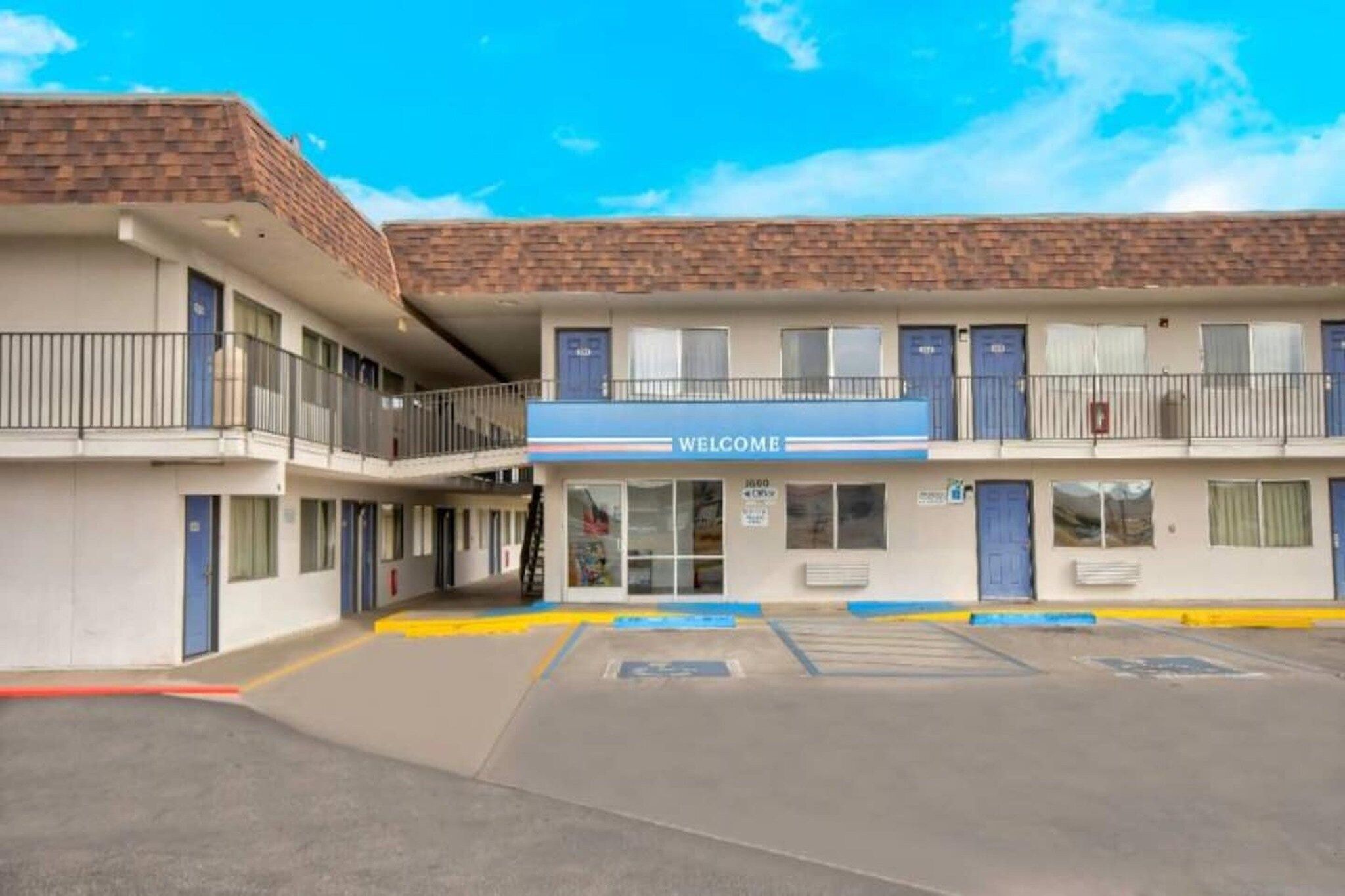 A motel with a 'WELCOME' sign, multiple floors, and a parking lot.
