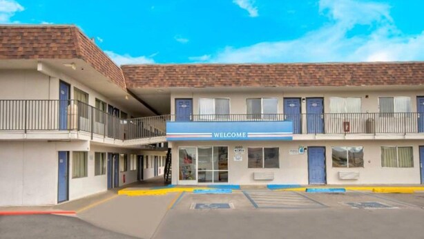 A motel with a 'WELCOME' sign, multiple floors, and a parking lot. - 1 Queen Bed | Deluxe, Micfridge (Farmington)