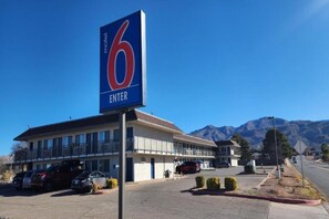A motel with a prominent '6 ENTER' sign, a parking lot, and a mountain backdrop. - 2 Full Beds|Smoking,Micfridge (Alamogordo)