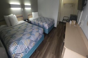 Hotellihuone, jossa on kaksi sänkyä, työpöytä ja tuoli.