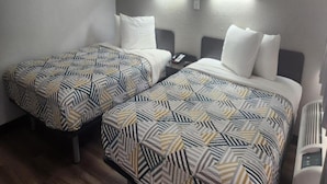 Une chambre d’hôtel avec deux lits, chacun agrémenté de draps à motifs, une table de chevet avec un téléphone et des lampes fixées au mur.