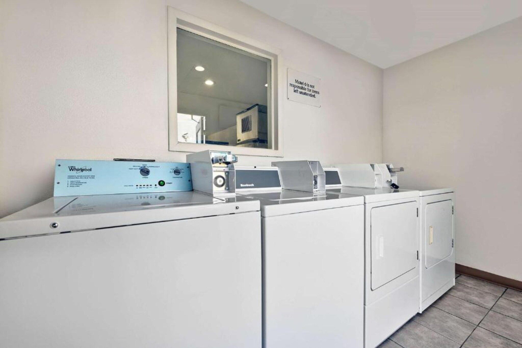 Un área de lavandería con lavadora y secadora Whirlpool, un panel de control y un cartel en la pared.