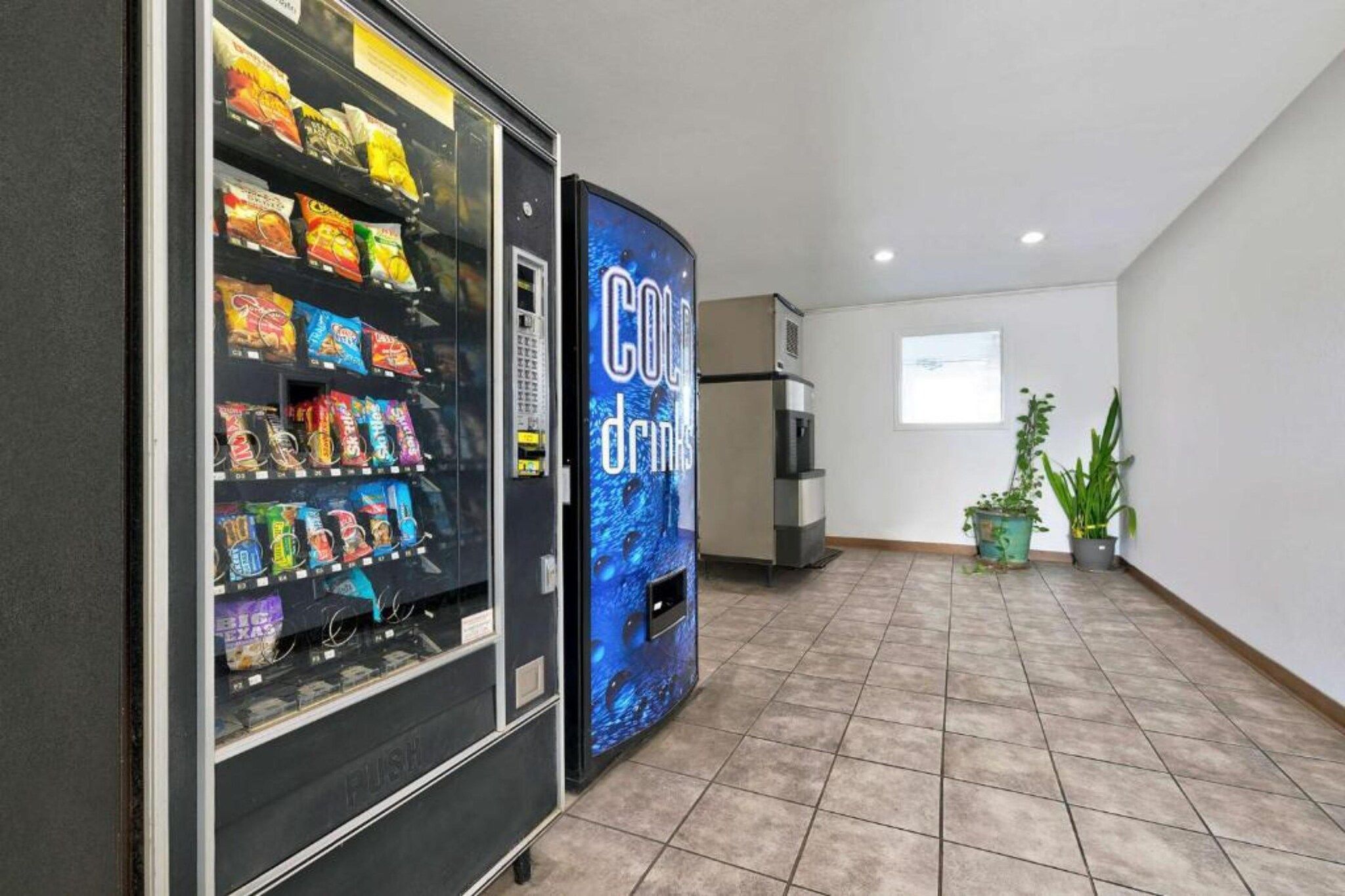 Zona de máquinas expendedoras con aperitivos y una máquina de bebidas frías.