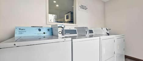 A laundry area with a Whirlpool brand washer and dryer, a control panel, and a sign on the wall.