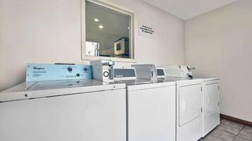 Un área de lavandería con lavadora y secadora Whirlpool, un panel de control y un cartel en la pared.