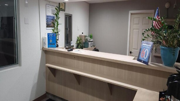 Una recepción con un letrero informativo azul, una planta en maceta y una bandera estadounidense.