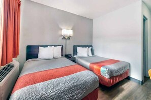 A hotel room with two beds, a nightstand, a lamp, and an air conditioning unit. - Spacious 2 Full Beds |Motel 6 Gallup, NM (Gallup)