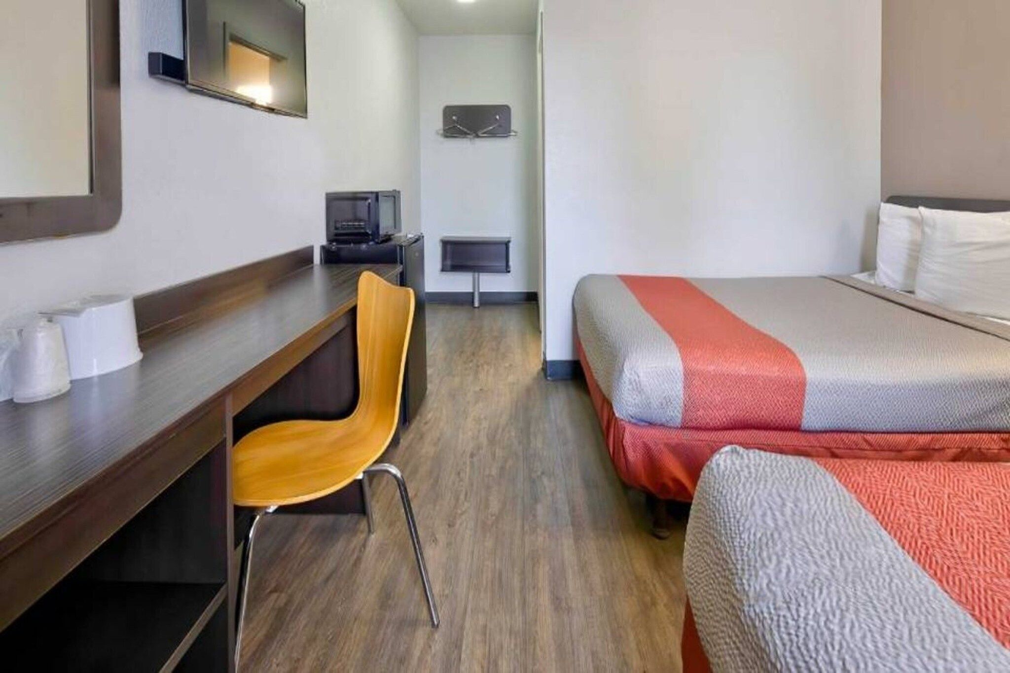 Een hotelkamer met een bureau, stoel, twee bedden, een televisie en een klein tafeltje.