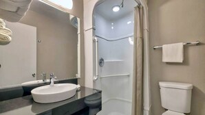 Een badkamer met een wastafel, spiegel, douche en toilet.