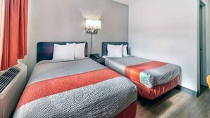 A hotel room with two beds, a nightstand, a lamp, and an air conditioning unit. - 2 Full Beds | Mobility Accessible Tub (Gallup)