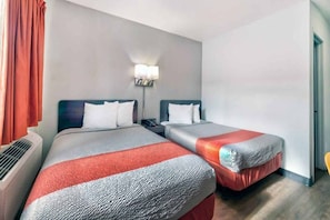 Een hotelkamer met twee bedden, een nachtkastje, een lamp en een airconditioner.