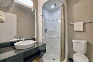 Een badkamer met een wastafel, spiegel, douche en toilet.