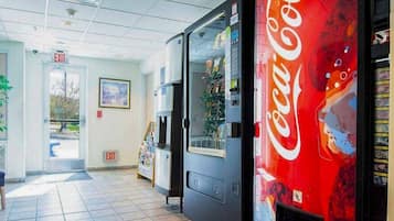 A vending machine with a Coca-Cola logo, a door with an exit sign, and a magazine rack.