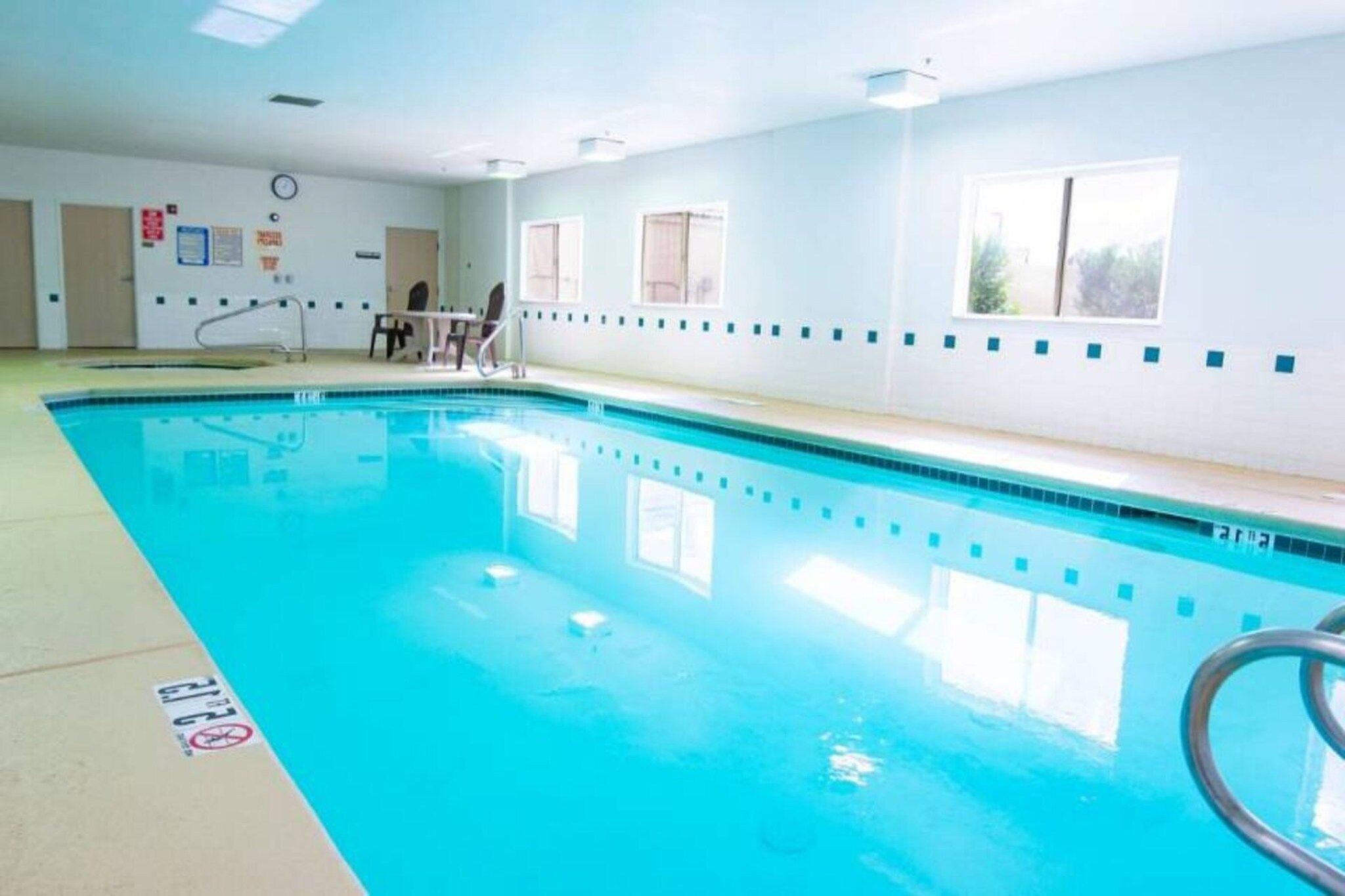 An indoor swimming pool with clear water, a starting block, and a lifeguard chair.