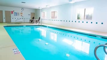 An indoor swimming pool with clear water, a starting block, and a lifeguard chair.