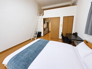 Ein Schlafzimmer mit einem Bett, einem Schreibtisch, einem Stuhl, einer Leiter und einem Kleiderschrank.