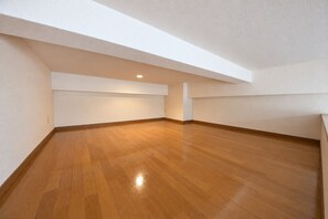 Ein Zimmer mit Holzboden, weißen Wänden und einer schrägen Decke.