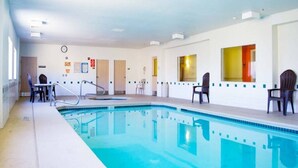 Piscina com plataforma de mergulho, cadeiras e porta que dá para outro cômodo.