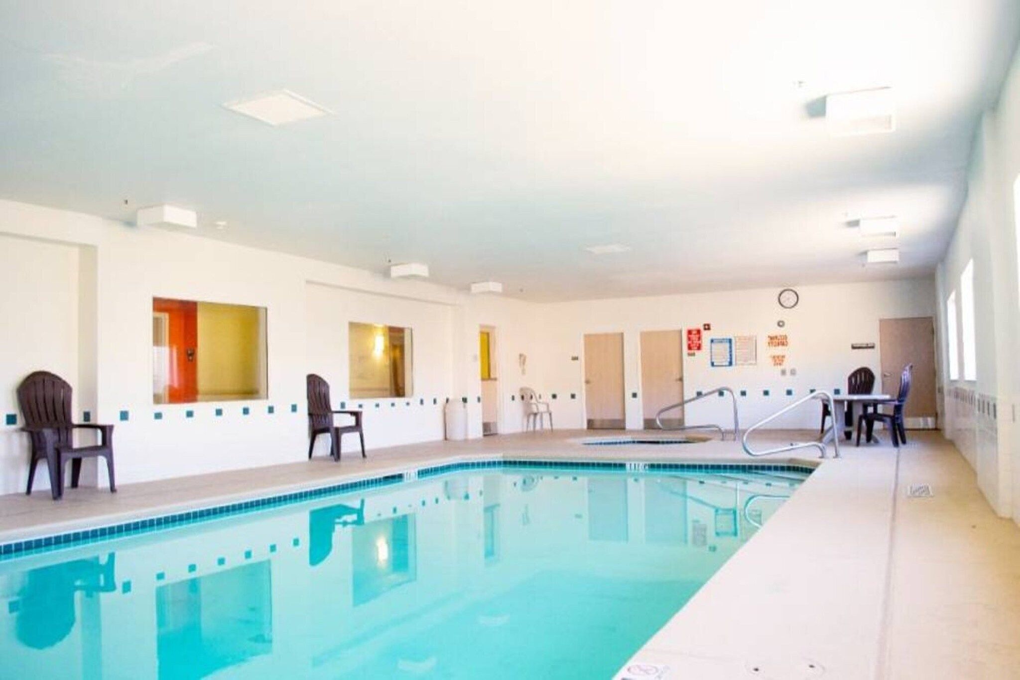 Una piscina con borde de azulejos, una silla de salvavidas y una sombrilla.