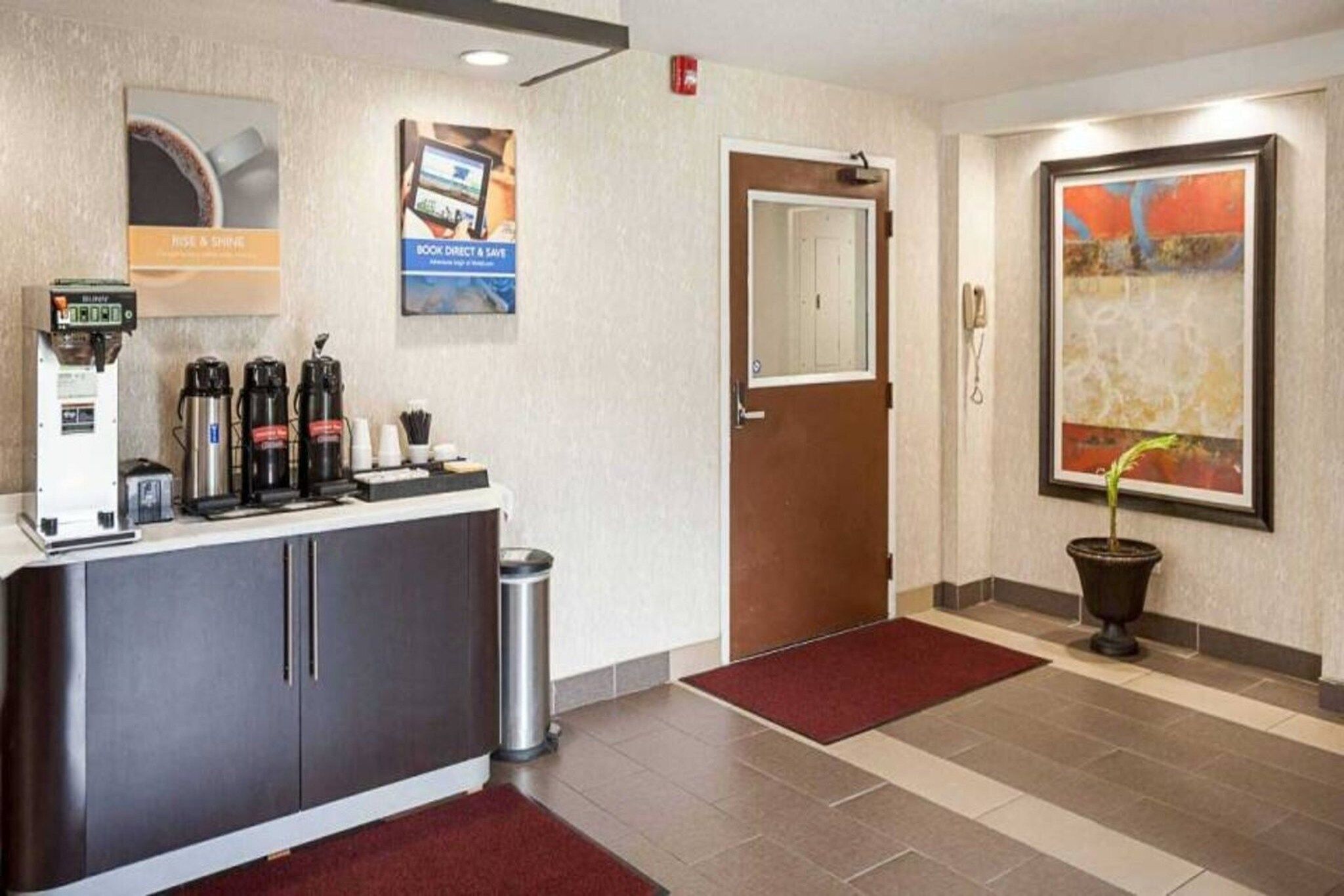 A hotel reception area with a coffee machine, a trash can, and a door.