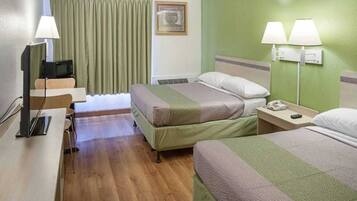 A hotel room with two beds, a desk with a computer, a chair, a television, and two bedside lamps.