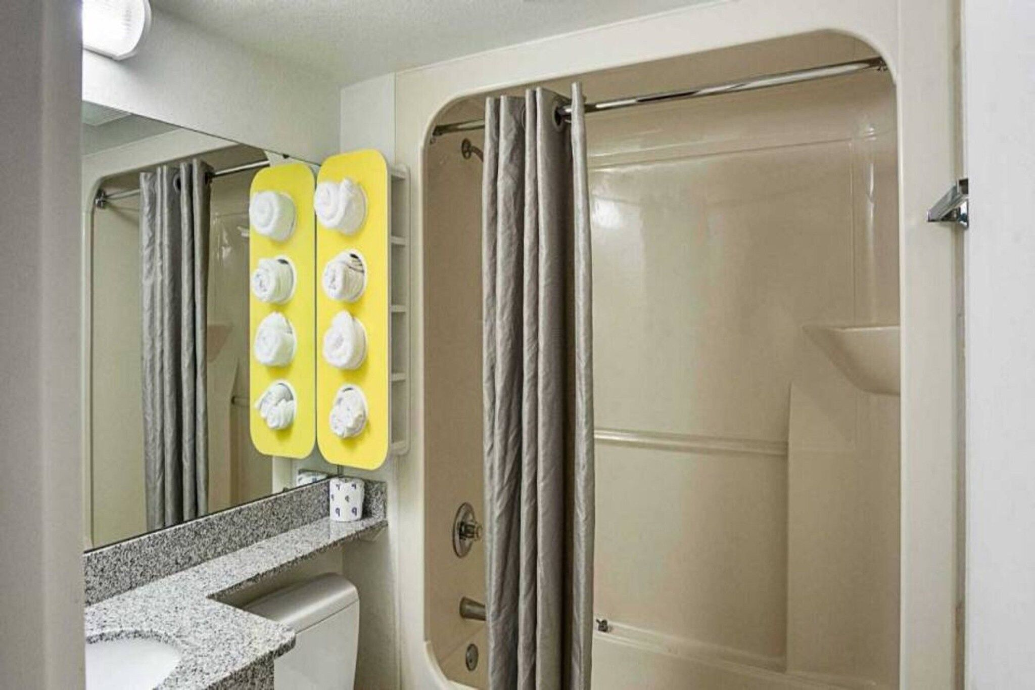 A bathroom with a shower, a toilet, and a sink with a mirror.